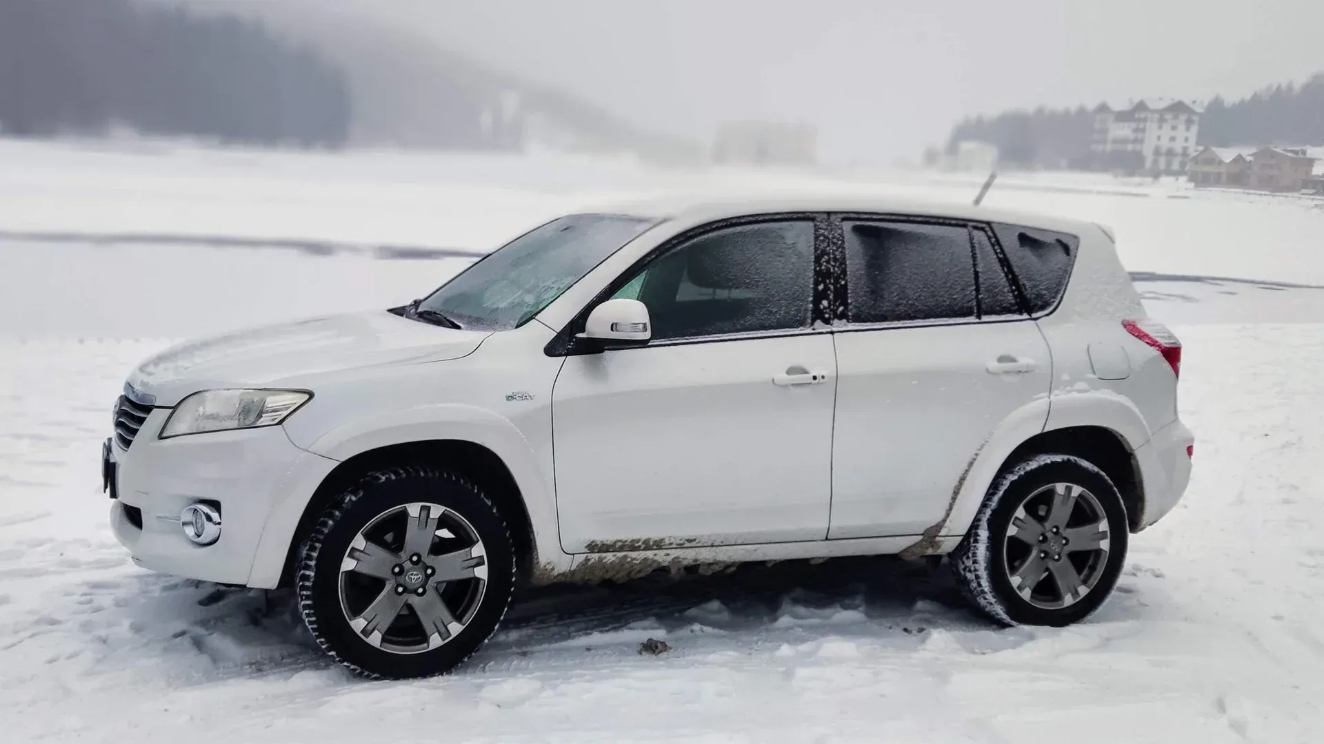 RAV4 preto em estrada com neve profunda nas Dolomitas, demonstrando a importância de pneus de inverno e tração 4x4.