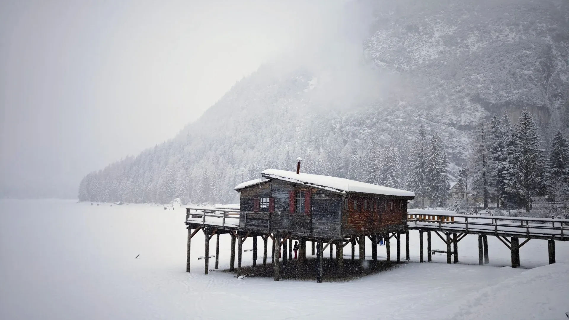 Lago di Braies no inverno com superfície parcialmente congelada e montanhas nevadas ao redor